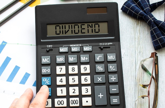 A calculator labeled DIVIDEND lies on financial documents in the office Business concept