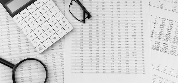 Calculator magnifying glass and eye glasses on financial statement Top view