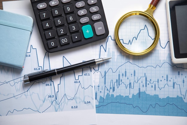 Calculator magnifying glass and other items with a financial graphs