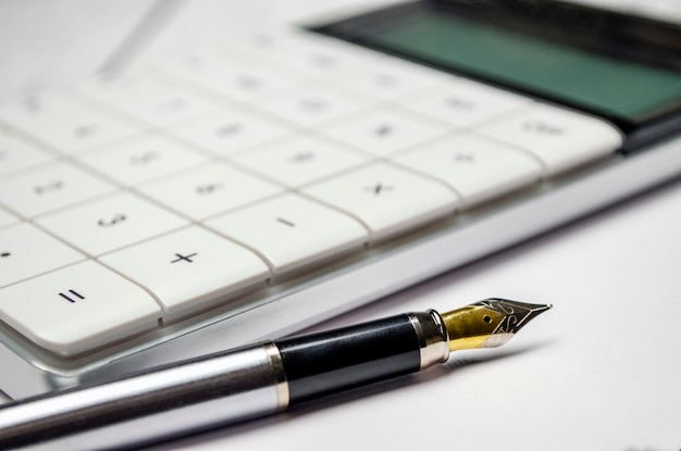 Calculator and a pen on the white background