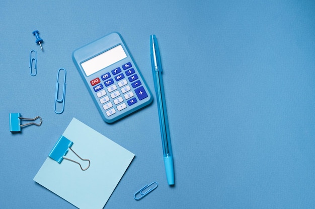 Calculator stationery accessories on blue background with copy space Look