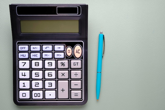 Calculator with a ballpoint pen on a leather texture background