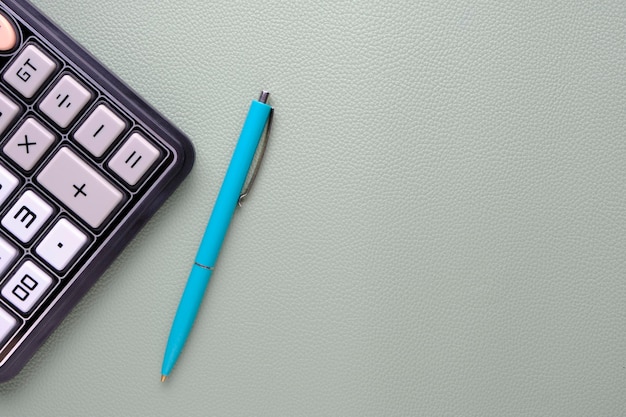 Calculator with a ballpoint pen on a leather texture background