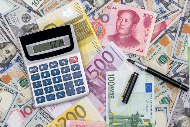 Calculator with euros, dolalr and yuan with pen on desk.