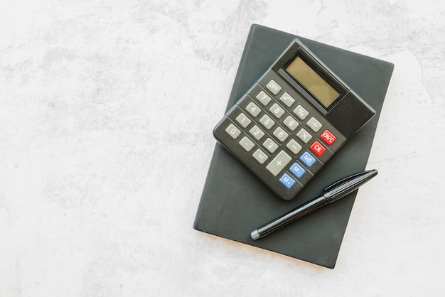 Calculator with notebook on table