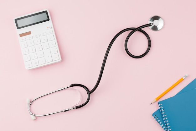 Calculator with a stethoscope on a pink table