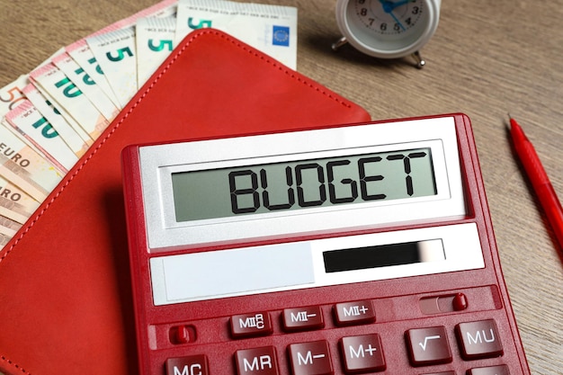 Calculator with word Budget notebook and money on table closeup