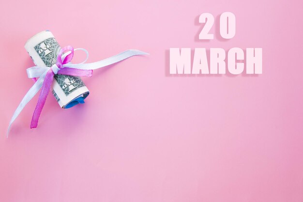 Photo calendar date on pink background with rolled up dollar bills pinned by pink and blue ribbon march 20