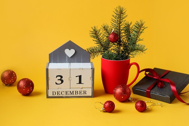 Calendar for December 31 : the name of the month in English, the number 31 ,a Christmas composition in a red cup, Christmas balls, a gift in a gray package, tied with a red ribbon