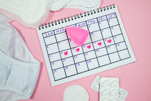 Calendar photo underwear menstrual cup sanitary napkins on isolated pastel pink background The concept of menstruation women's creative days