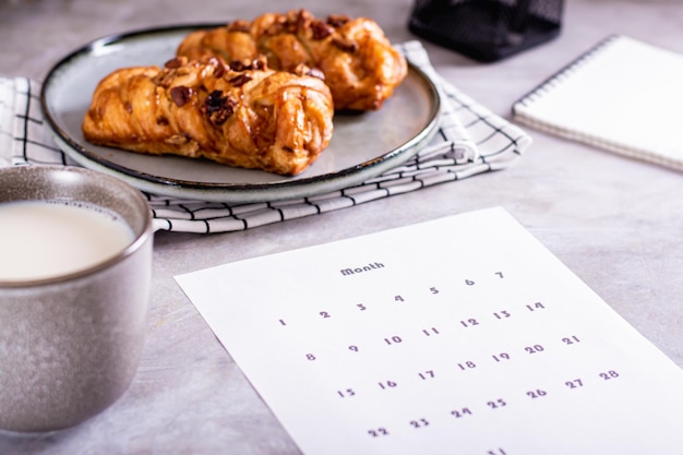 Calendar sheet for planning during a snack with latte and buns in fika time