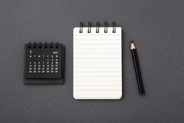 Calendar with notebook on black stone background