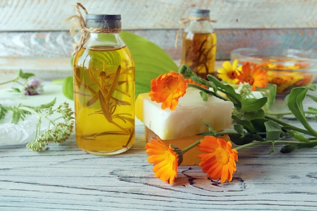 Calendula flowers soap oils and tinctures on a wooden background natural ingredients