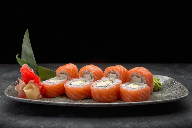 California sushi roll with cucumber avocado cream cheese and salmon on a gray plate on a dark table