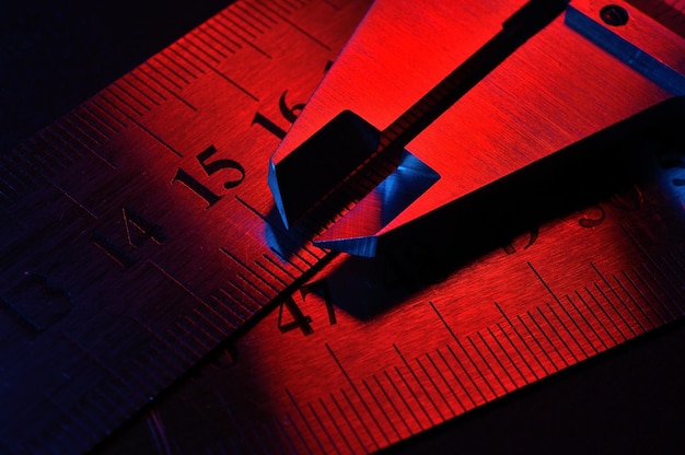 Caliper and metal rulers illuminated in red and blue closeup