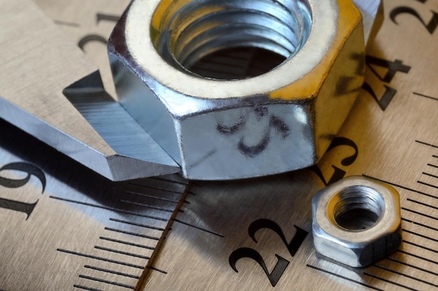 Caliper and nuts with a bolt a metalwork measuring tool lies on the background of metal rulers closeup