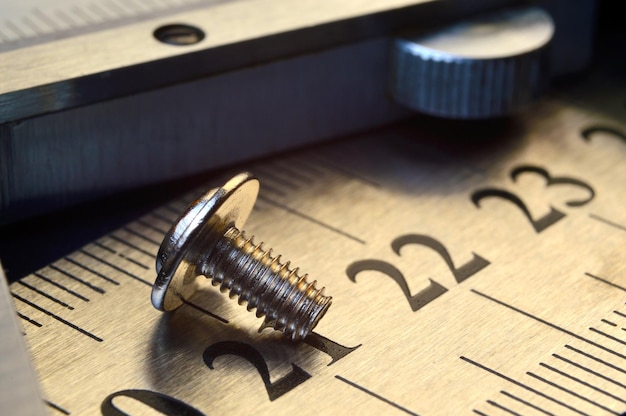 Caliper and nuts with a bolt a metalwork measuring tool lies on the background of metal rulers closeup