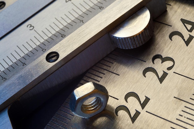 Photo caliper and nuts with a bolt a metalwork measuring tool lies on the background of metal rulers closeup