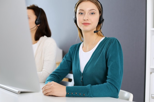 Photo call center group of operators at work focus on beautiful woman receptionist in headset