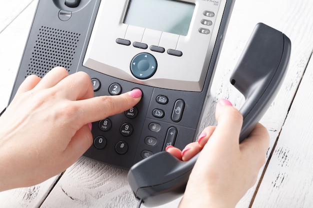 Photo call center or office phone concept, female finger press number on phonepad