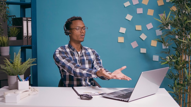 Call center operator having argument with client on helpline using headset with microphone and laptop at desk. Telemarketing employee yelling at person at customer support service.