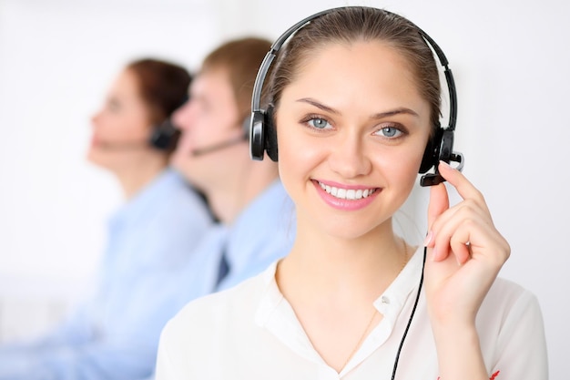 Call center operators. Young beautiful business woman in headset. Call center. Male call operator in headset at the background.