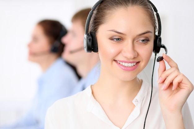 Call center operators Young beautiful business woman in headset Male call operator in headset at the background