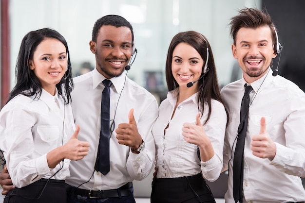 Call center workers are smiling and looking at camera.