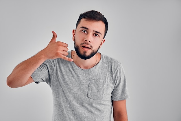 Call me! Handsome young man showing a call me sign isolated on grey background