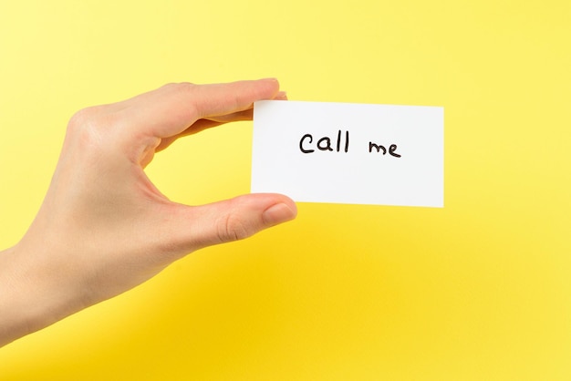 Call me text on a card in woman hand  on a yellow background