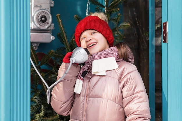 Calling to Santa Claus. Little Girl Child Call Santa order Christmas Gifts in Phone Booth on Street.