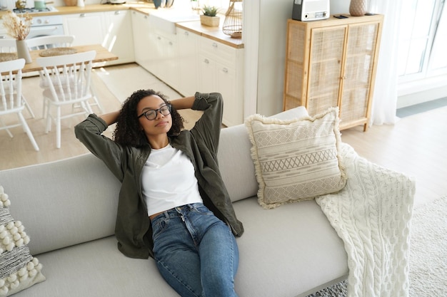 Calm african american girl enjoy fresh conditioned air resting sitting on cozy sofa in living room