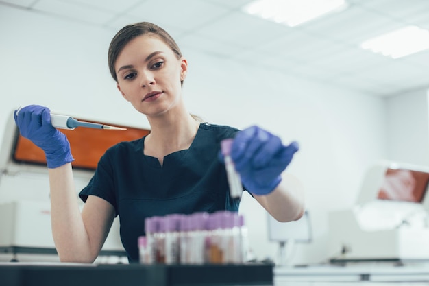 Calm laboratory assistant carefully putting a test tube into a tube holder