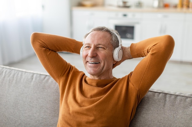 Calm mature man having rest at home listening to music