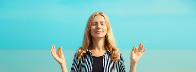 Photo calm relaxing healthy young woman meditates practicing yoga enjoying on the beach on sea blue sky