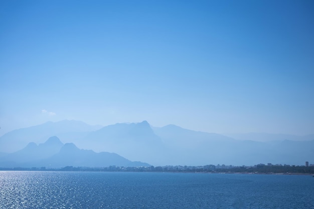 Calm sea against backdrop foggy mountains and blue sky travel concept