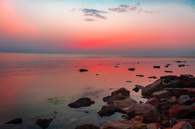 A calm sea with a sunset sky and the sun through the clouds overhead Meditation ocean and sky Calm seascape The horizon above the water