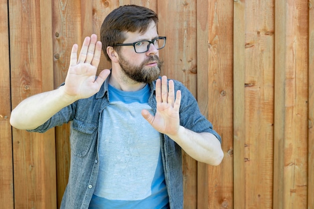 A calm selfconfident bearded man pus his palms as a defense or calming someone down