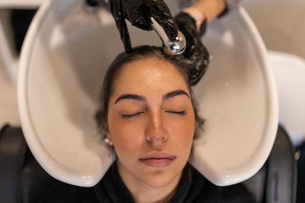 Calm woman getting hair wash in sink