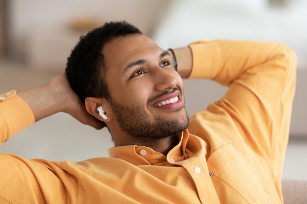 Calm young man having rest at home listening to music