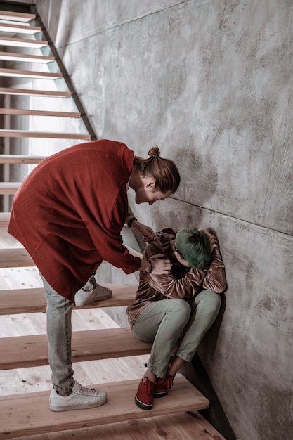 Calming girlfriend. Boyfriend calming his emotional girlfriend sitting on stairs and crying after big fight