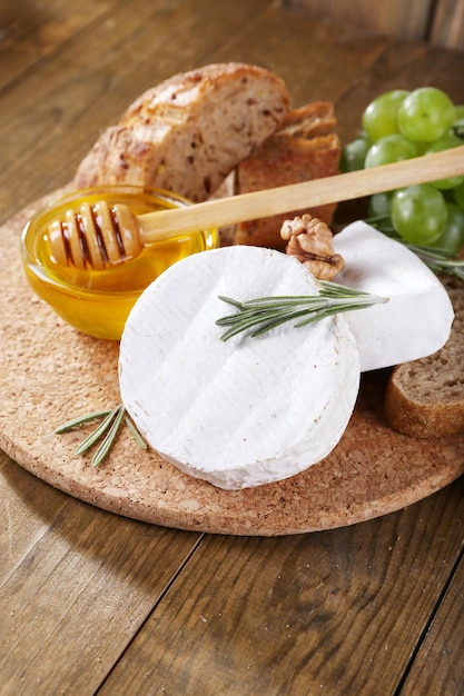 Camembert cheese bread honey and grapes on cutting board on wooden background