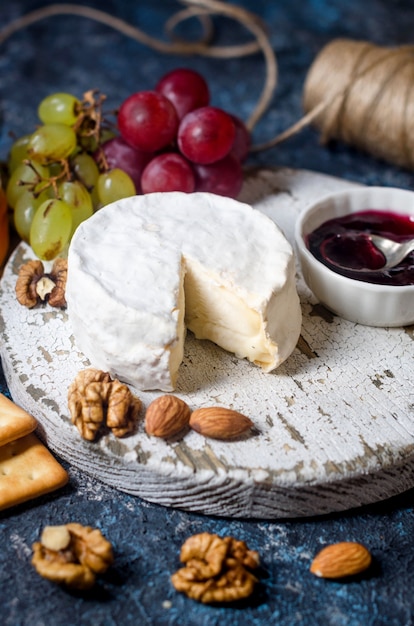 Camembert cheese close-up with honey, nuts, vine. Exquisite cheese plate, wine food. 