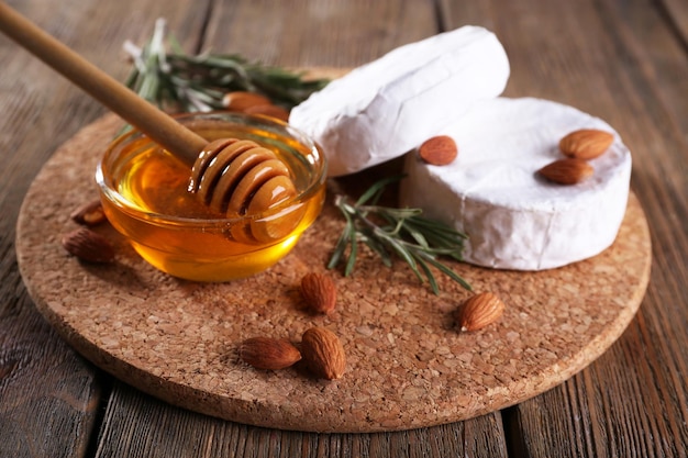 Camembert cheese honey in glass bowl and nuts on wooden background