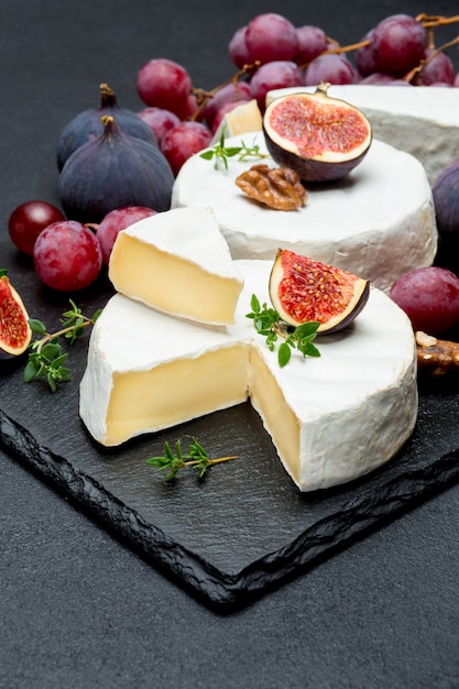 Camembert cheese and a slice cut on stone serving board