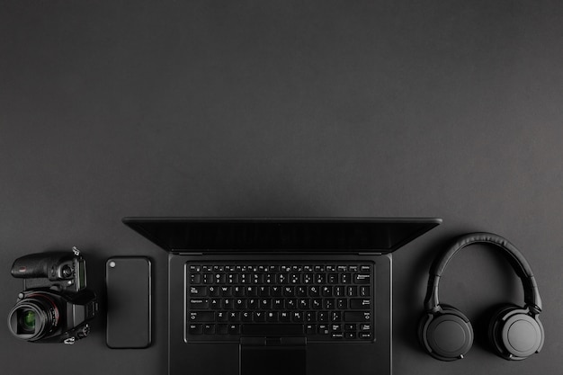 Camera and laptop on black minimal table top view. Copy space. Minimal abstract background. Creative flat lay.