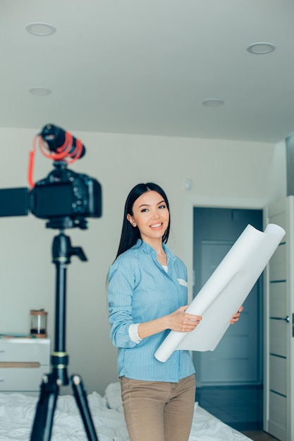 Camera and microphone on tripod in the bedroom Confident young architect blogger recording a video and smiling