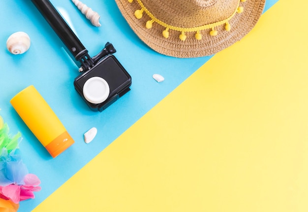 Camera straw hat seashells and sunglasses on a yellow background