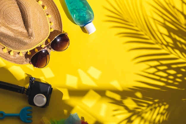 Camera straw hat sunblock and sunglasses on a yellow background