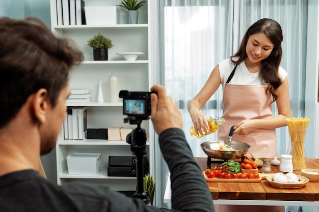 Cameraman recording to woman in chef influencer cooking spaghetti Postulate